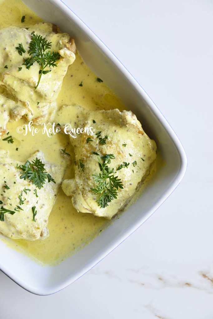 Roasted Chicken Thighs with Creamy Mustard Sauce in a blue and white casserole dish