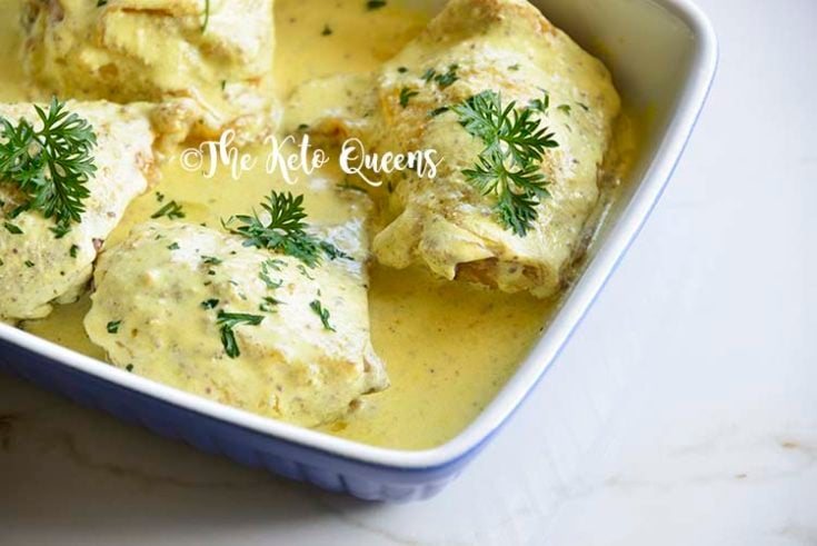 Roasted Chicken Thighs with Creamy Mustard Sauce in a blue and white casserole dish sprinkled with parsley