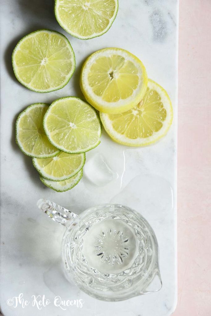 keto simple syrup in a glass with lemons and limes on a marble slate