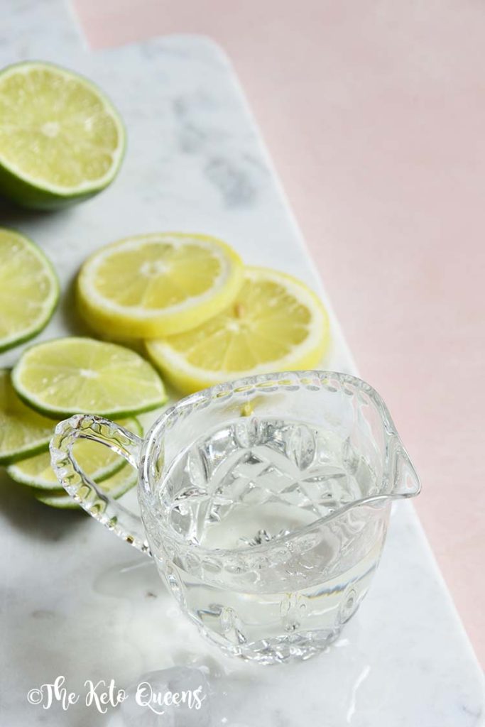 keto simple syrup in a glass with lemons and limes on a marble slate