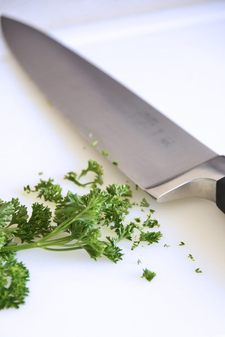 Fresh parsley cut up next to a knife