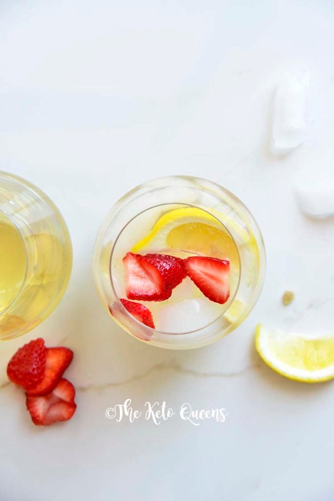 iced strawberry lemon tea in a seamless wine glass with lemon wedges